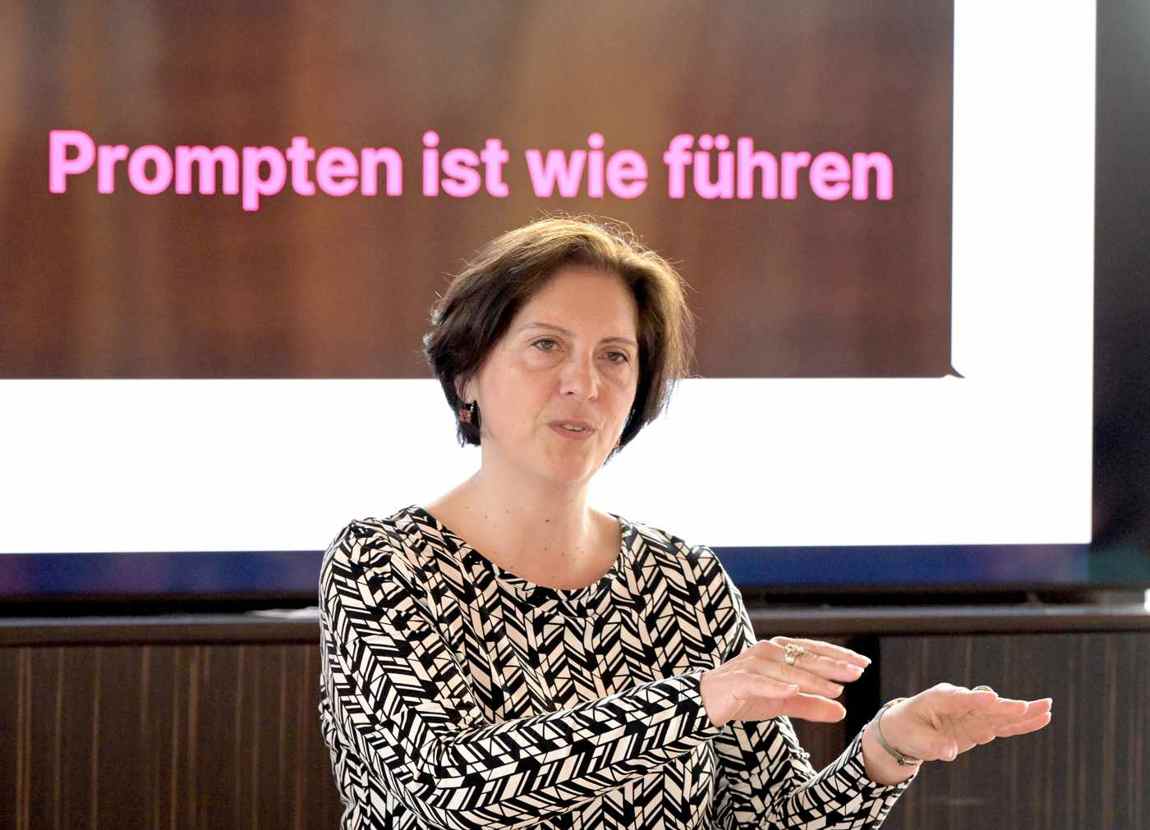 Martha Giannakoudi vor der Leinwand mit dem Satz Prompten ist wie führen